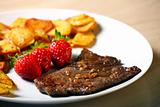 Beef steak with sliced potatoes and strawberries