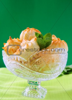 Cake profiteroles  in a crystal vase on a green background