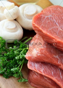 Fresh raw beef  with mushrooms and parsley  on wooden cutting board