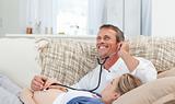 Man listening his wife's belly with his stethoscope
