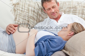 Happy pregnant woman with her husband on their sofa