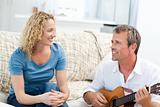 Romantic man playing guitar for her wife at home
