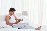 Man reading a book on his bed 
