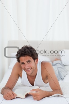 Man reading a book on his bed 