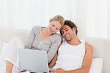 Adorable couple looking at their laptop on the bed at home