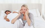 Attractive woman having a headache while her husband is sleeping
