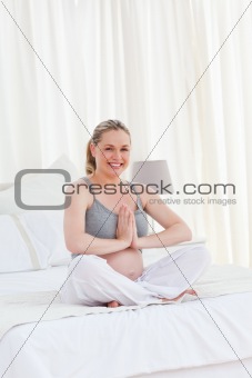 Pregnant woman practicing yoga on her bed