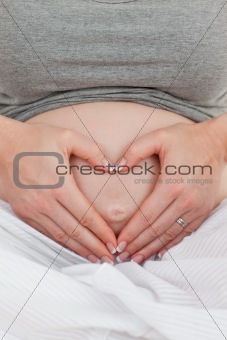 Pregnant woman doing heart sign on her belly