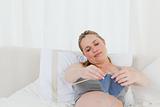 Adorable pregnant woman knitting on her bed