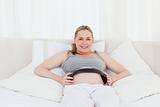 Pregnant woman putting her earphones on her belly