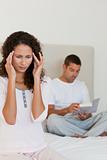 Woman having a headache while her husband is reading