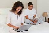 Woman working on her laptop while her husband is reading