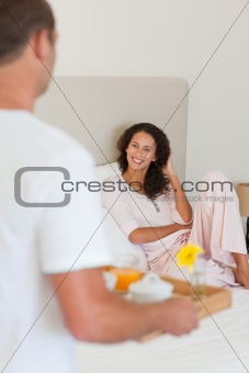 Man bringing the breakfast to his wife in bed