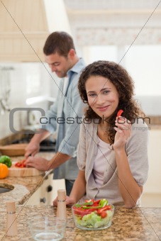 Woman eating while her husband is cooking