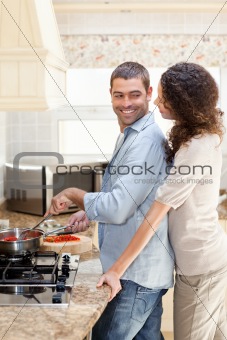 Woman hugging her husband while he is cooking