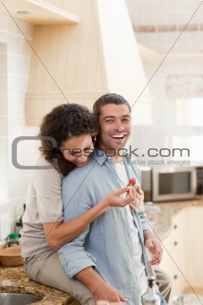 Lovers eating a strawberry in their kitchen