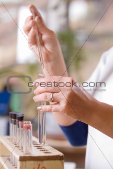 Woman pours a drop of liquid in a flask