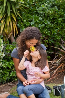 Mother smelling a flower with her daughter