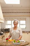 Retired woman looking at the camera in the kitchen