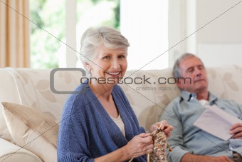 Woman knitting while her husband is sleeping