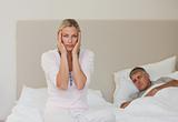 Woman having a headache while her husband is sleeping