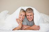 Couple lying down in their bed at home
