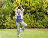 Mature woman doing her streches in the garden