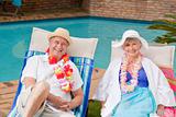 Senior couple lying down beside the  swimming pool