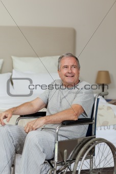 Smiling senior man in his wheelchair  at home