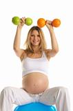 pregnant  is engaged in fitness dumbbells fruit