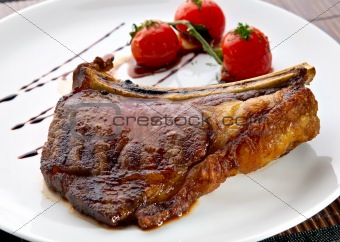 Grilled meat ribs on white plate with tomatoes