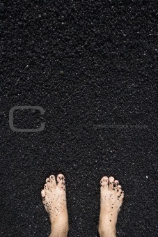 Barefeet in black sand.