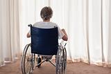 Mature woman in her wheelchair with her back to the camera at ho