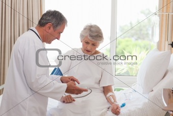 Mature doctor taking the blood pressure of his patient