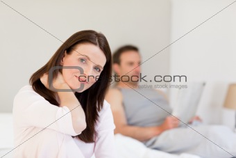 Lovely woman looking at the camera while her husband is sleeping