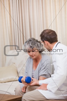 Handsome doctor helping his patient to do exercises