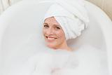 Lovely woman taking a bath with a towel on her head 