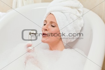 Charming woman taking a bath with a towel on her head 