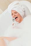 Charming woman taking a bath with a towel on her head 
