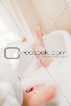 Pretty woman taking a relaxing bath with a towel on her head 