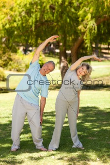 Mature couple doing their streches in the park