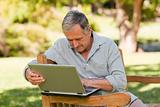 Retired man working on his laptop in the park