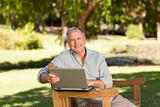 Retired man working on his laptop in the park