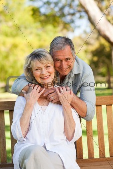 Elderly man hugging his wife who is on the bench