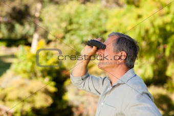 Senior man looking at the sky with his binoculars