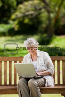 Mature woman working on her laptop on the bench