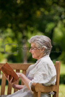 Reired woman reading a book on the bench