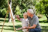 Happy Grandfather and his grandson painting in the garden