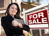 Proud, Attractive Hispanic Female Agent In Front of For Sale Real Estate Sign and House.