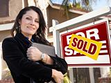 Proud, Attractive Hispanic Female Agent In Front of Sold For Sale Real Estate Sign and House.